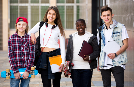 Fashionable group of teenager posing outside school with papers for studyの写真素材
