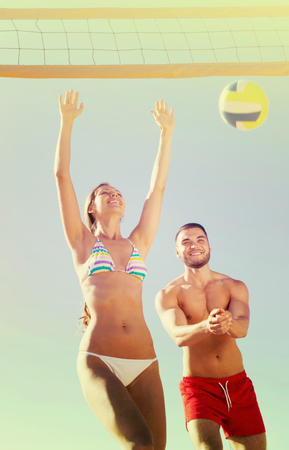 Young couple playing volleyball at sea beachの写真素材