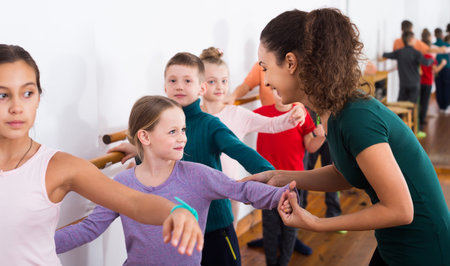 Group of smiling european children practicing at the ballet barre