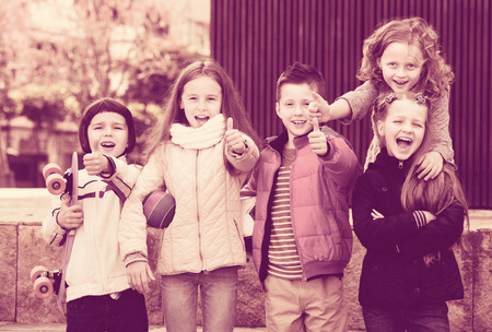 Positive little kids showing thumbs up in city streetの写真素材