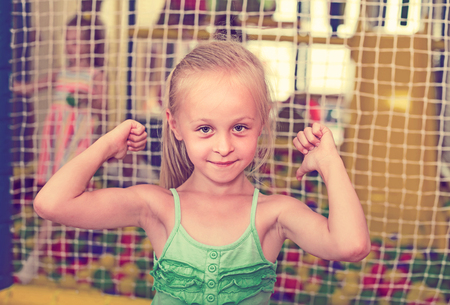 smiling girl in bright dress looking happy and standing on indoor playgroundの写真素材