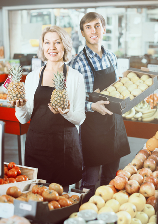 Smiling two workers  posing with fruits in local supermarketの写真素材