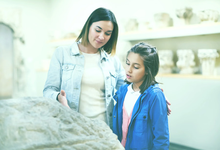 Young mother and daughter exploring old bas-reliefs in museum. Focus on childの写真素材