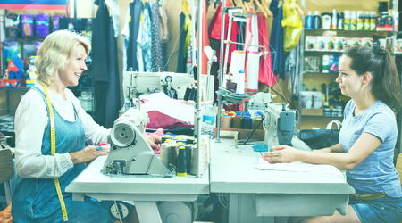 Portrait of two professional experienced female tailors working in sewing workshopの写真素材