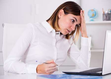 Young female worker having problem in project in officeの写真素材
