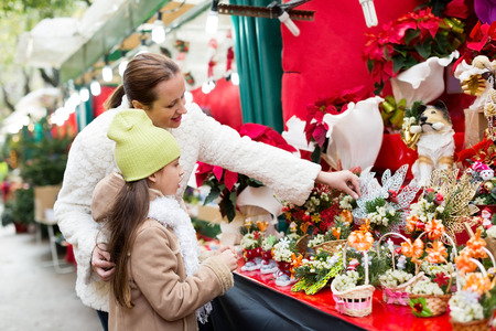 little daughter with mother choosing mistletoe decorations for Xmas. Focus on womanの写真素材