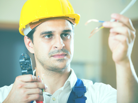 Professional electrician working with wires at client homeの写真素材