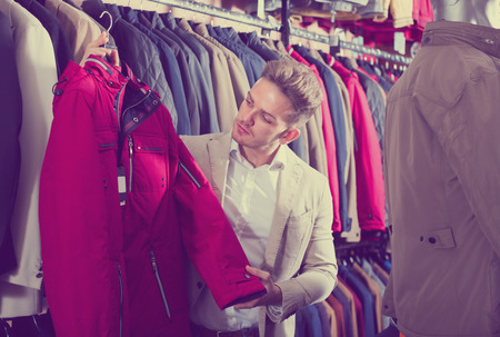 Ordinary male customer examining coats in mens cloths storeの写真素材