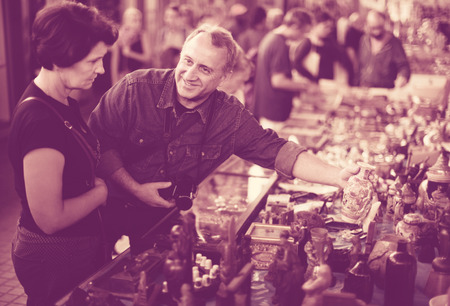 Elderly man and woman aged consider things in flea marketの写真素材