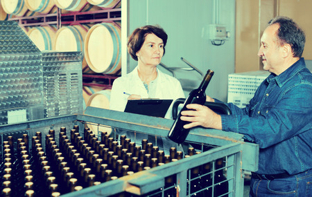 Wine maker showing to expert of the bottles with wineの写真素材