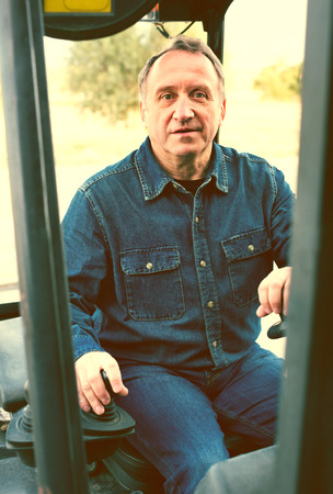 Mature male worker goes on loaderの写真素材