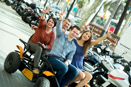 Family of four sitting in grand tour electric and taking pictures of Europenian cityの写真素材