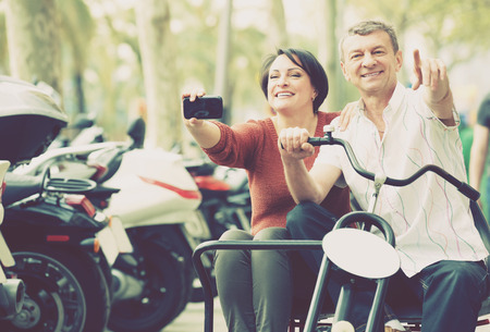 Mature man and woman traveling through city by twin  bicycleの写真素材