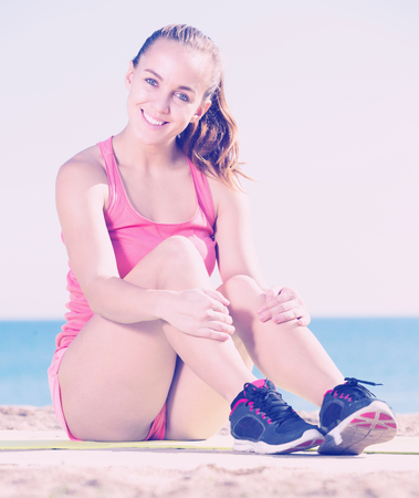 Positive adult sporty woman exercising at sea beachの写真素材