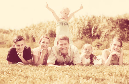 Man and woman with four kids lying in park on summer day