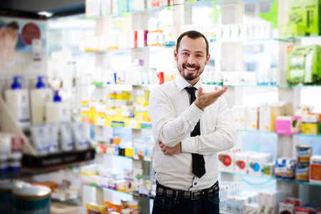 Positive male customer searching for reliable drug in pharmacyの写真素材