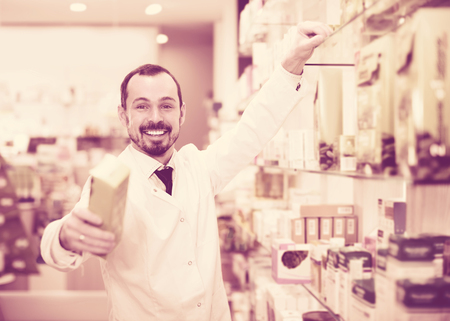 Smiling man pharmacist offering right drug in  drugstoreの写真素材
