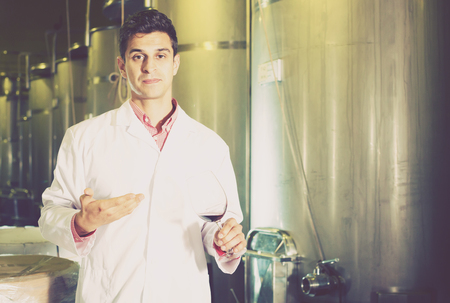 Male sommelier checking wine fermentation in winery interiorの写真素材
