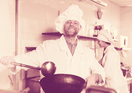 Cheerful professional chefs working in restaurant kitchenの写真素材