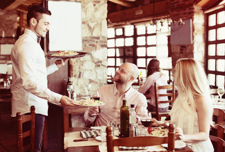 smiling people having dinner at rural restaurant. Focus on the manの写真素材