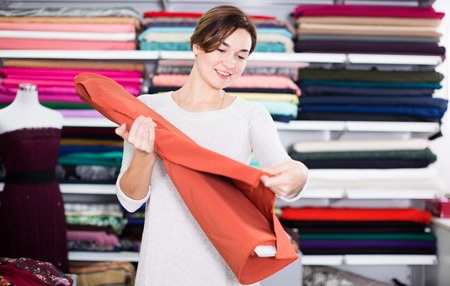 Girl customer looking for beautiful fabric in drapery shopの写真素材