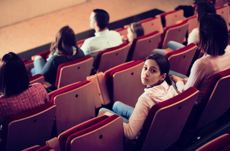 Girl turning around from screen in cinema houseの写真素材