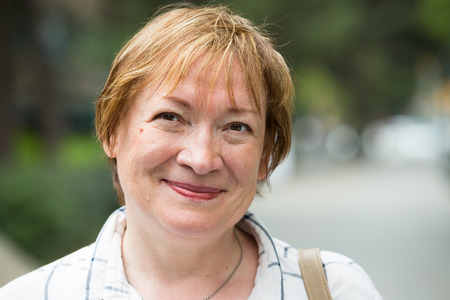 closeup on smiling senior woman outdoors on sunny summer dayの写真素材