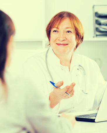 Female visitor consulting smiling woman doctor in hospitalの写真素材