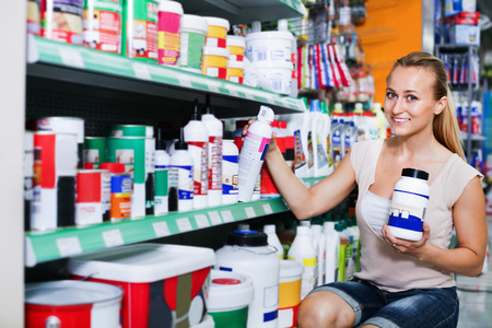 Glad woman customer looking for paint solvent in bottle in household storeの写真素材