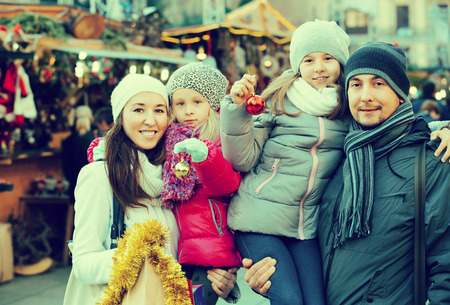 Family with children purchasing Christmas decoration and souvenirs at fair. Focus on all peopleの写真素材