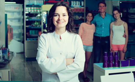 portrait of glad spanish female druggist in white coat working in pharmacyの写真素材