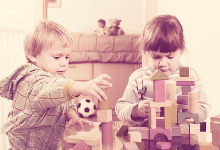 Two tranquil children playing with wooden blocks  in home interiorの写真素材