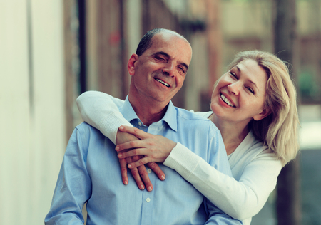 Happy mature family hugging together at walking through streetの写真素材