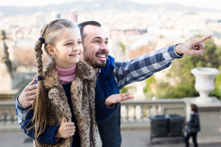 Positive man and small daughter looking at sight during sightseeing tourの写真素材