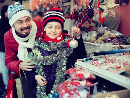 Happy man with small daughter near the customer counter with Christmas garlandsの写真素材