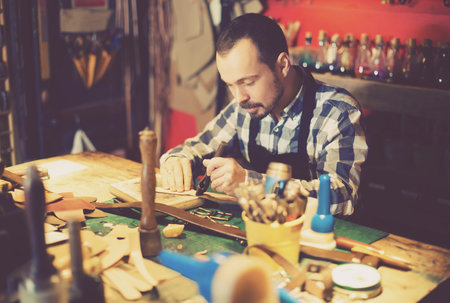 Professional man worker working on belt leather in leather workshop