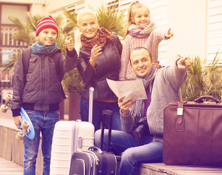Happy middle class family of four checking a direction in a city map outdoorの写真素材