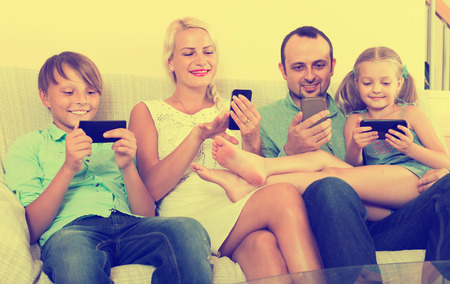 Portrait of positive european family playing with gadgets at homeの写真素材