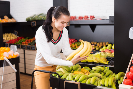 Smiling girl deciding on fruits in grocery shopの写真素材
