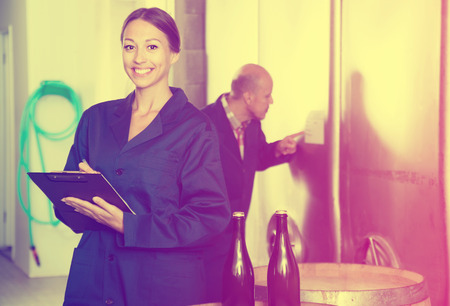 Portrait of woman standing with cardboard in hands in fermentation compartment on factoryの写真素材