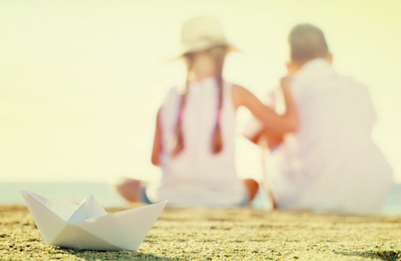 Close up view on origami paper boat toy with two kids blurred on backgroundの写真素材