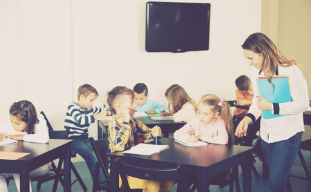 Portrait of boys and girls with teacher drawing in classroomの写真素材