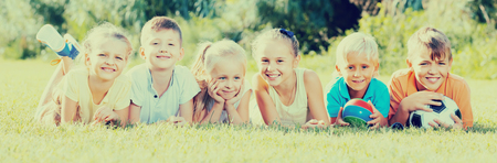 portrait of smiling american children lying on grass in park and looking happyの写真素材