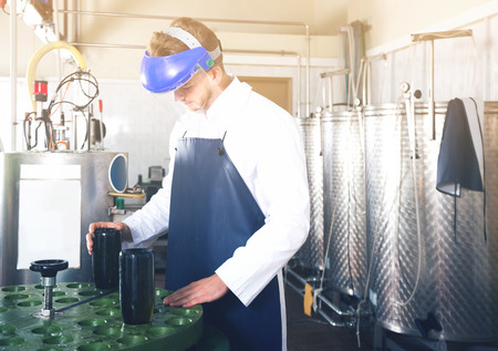 adult male employee operating machine at sparkling wine factoryの写真素材