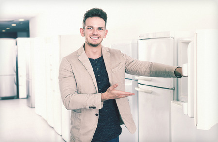 Ordinary male customer looking at modern fridges in hypermarketの写真素材