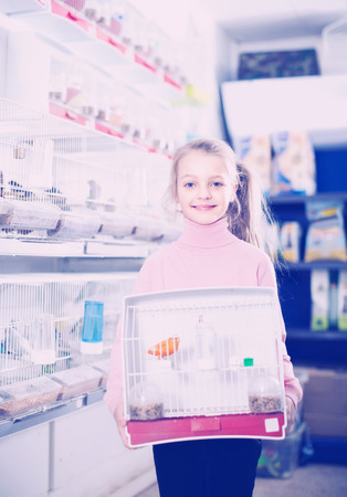Smiling girl customer enjoying her purchase of canary bird in pet shopの写真素材