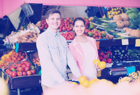 Smiling young customers buying oranges, lemons and tangerines in grocery sectionの写真素材