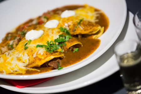 Mexican enchilada corn tortilla covered chili pepper sauce in plateの写真素材