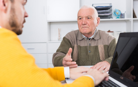 Aged man signing financial agreement in office with managerの写真素材