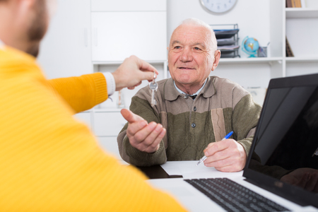 Old man and agent sign lease contract of apartment in agencyの写真素材